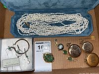 Overall view of box containing pearls, earrings, pendants, watches, pin