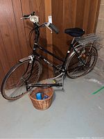 Full view of black Norco bicycle with wicker basket at front and rear rack
