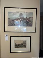Two framed hunting scene prints on a beige wall, one larger and one smaller below