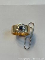 Top-down view showing ring on white background with paperclip for scale