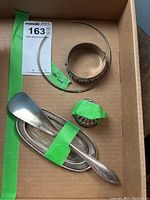 Top down photo showing all items in lot: bangle bracelet, ring holder lid, shoe horn with tray, and necklace.