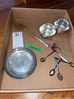 Overall view of two sterling bowls, shallow bowl, wood-handled spoon, and six colored-handle teaspoons arranged in box