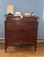 Front view of the vintage wood dresser showing four drawers with decorative metal hardware and carved details.
