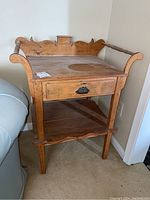 Front angled view of pine wash stand showing surface wear, drawer, towel rungs, and carved backboard.