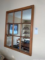 Full view of the wooden framed 9 pane mirror mounted on a light-colored wall, showing the overall condition and reflections.