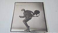 Front cover of Bryan Adams 'Cuts Like a Knife' vinyl record album with image of Bryan Adams jumping with guitar.