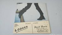 Front album cover showing legs and feet photo with Lodger text and David Bowie details.
