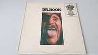 Front cover of 'The Best Of Dr. Hook' vinyl album featuring a close-up color photo of a man from the band sticking out his tongue and the album title.