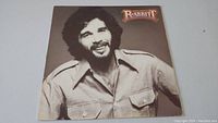 Front cover of Eddie Rabbitt 'Rabbitt' vinyl record album featuring a brown-toned photo of Eddie Rabbitt smiling and wearing a casual shirt.