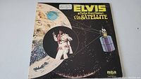Front cover of Elvis Presley Aloha From Hawaii Via Satellite LP album showing space illustration with satellite and Elvis performing.