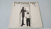 Front cover of Fleetwood Mac vinyl LP album showing black and white photo of two band members, one with cane, one gesturing.