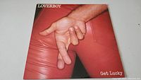 Front cover of Loverboy 'Get Lucky' LP showing close-up image of red pants and hand gesture