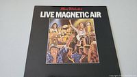 Front cover of Live Magnetic Air album showing band illustration and title text.