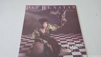 Front cover of Pat Benatar Tropico vinyl record album showing Pat Benatar seated and holding a bird over a chessboard patterned floor.
