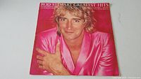 Front cover of Rod Stewart Greatest Hits album showing portrait of Rod Stewart in bright pink satin jacket