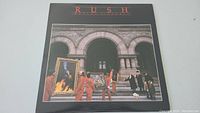 Front cover of Rush Moving Pictures album showing the artwork of people carrying framed paintings.