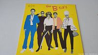 Front cover of The B-52's vinyl record album showing bright yellow background and band members illustration.