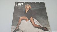 Front cover of 'Private Dancer' vinyl album showing Tina Turner in black outfit sitting with legs crossed.