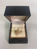 Front view of the 10K gold ring in black jewelry box showing diamond-shaped open lattice top design.