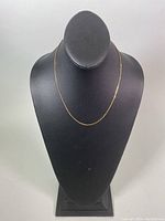 Full view of thin gold chain on display bust