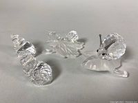 Photo of four Swarovski crystal figurines: large snail on frosted leaf and three smaller shell pieces