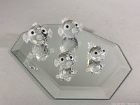 Four Swarovski Austrian crystal puffer fish figurines on beveled mirrored base, clear faceted crystal bodies with frosted fins and tails.