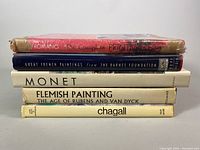 Five vintage art reference books stacked horizontally with titles visible showing 'The Complete Printmaker', 'Great French Paintings from The Barnes Foundation', 'Monet', 'Flemish Painting The Age of Rubens and Van Dyck', and 'Chagall'.