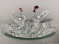 Group shot of two adult birds and six chicks on oval beveled mirrored base