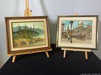 Two framed paintings on easels, showing overall condition and style