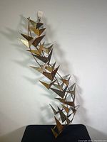 Full view of metal bas-relief wall sculpture leaning against a white wall