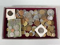 Tray with assorted old international coins in varied metal tones and sizes, some in protective holders.