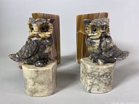 Front view of marble owl bookends on white marble bases with onyx slab bookends behind.