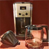 Front view of coffee maker with carafe and filter basket removed, showing stainless steel body and carafe space