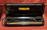 Top view of Freshlocker vacuum sealer open showing sealing area and power cord laid inside.