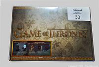 Front face of sealed Game of Thrones collector box showing ornate golden design and series logo with visible sticker.