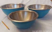 Three nested mixing bowls with stainless steel interiors and blue melamine outer surfaces.