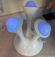 Front view of tri-light night light showing three arms with removable blue glowing balls on white base.