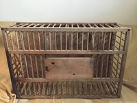Photo of rectangular wooden chicken crate with vertical slats and hinged access door.