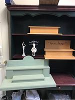 Photo showing three wooden shelves (two natural wood and one green painted), two figurine jewelry displays (female figure and white reindeer), and a tiered wooden spinning display.