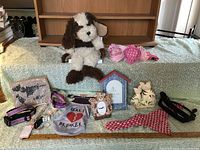 Photo of dog and cat related accessories including collars, bandanas, plush toy, bib, and wooden decorations.