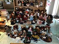 Group shot of approximately 30 Lizzie High cloth rag dolls displayed on a wooden shelf and tabletop