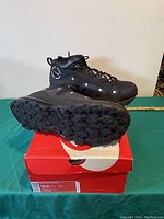 Men's black high-top Nike shoes with lugged sole on top of red Nike shoe box, size 10.5 visible on box label