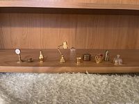 Wide shot of miniature brass and glass desk accessories and containers lined on a wooden shelf