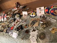 Wide shot of the pins spread out on carpet showing various themes: angels, sports, states, Christmas, and miscellaneous pins, many still in plastic packaging.