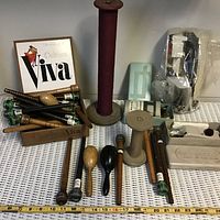 Wooden spools of thread, wooden sewing tools, and a Viva brand wooden box displayed on a white surface.