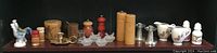 Photo showing an assortment of salt and pepper shakers, wooden containers, ceramic pieces and brass candle holder.