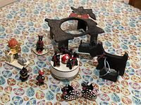 Overview photo showing wooden Scottie dog trivet, musical carousel, and several Scottie dog figurines and napkin rings on a patterned tablecloth.