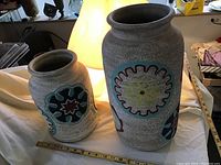 Two large pottery vases side by side showing decorative circular floral designs.