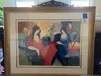 Framed serigraph titled The Secret by Itzchak Tarkay showing three women around a floral centerpiece.