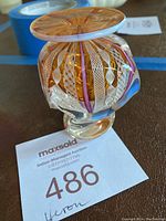 Photo showing the full vase with visible intricate patterns inside transparent amber-colored glass and a broad flat rim.